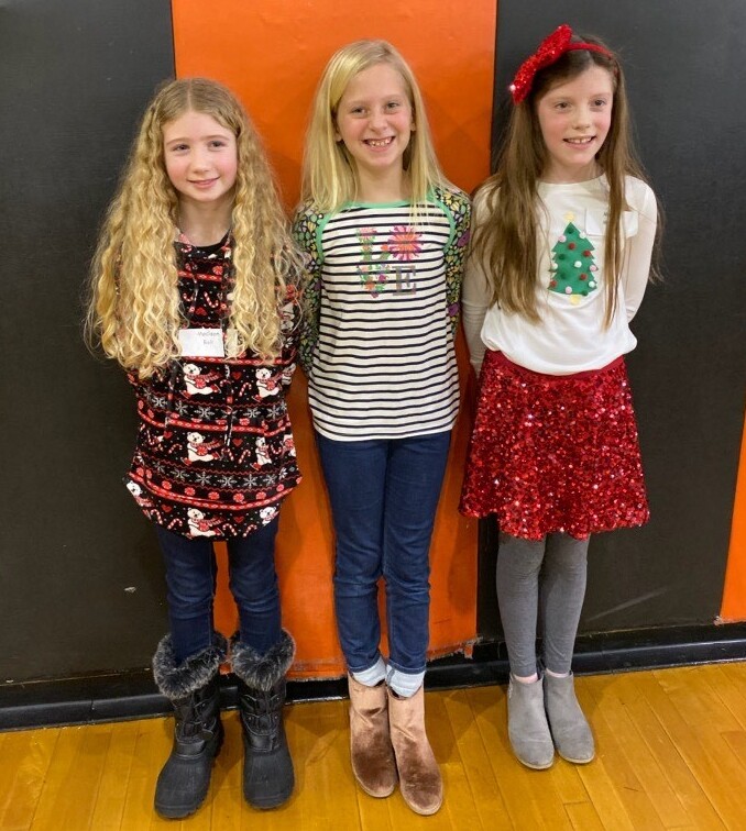 3 girls standing in front of orange and black